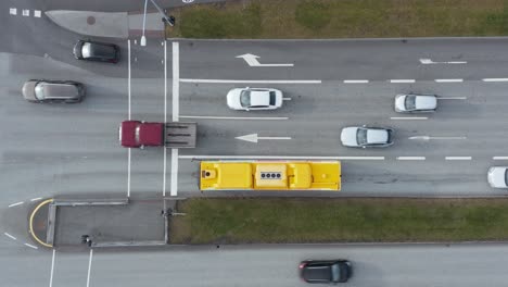 Cars-moving-along-crossing-intersection-during-green-traffic-light,-yellow-public-transport-bus,-top-down