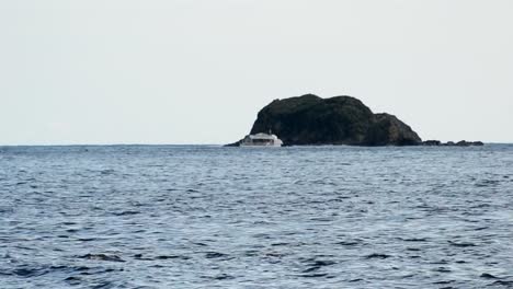 Barco-Navegando-Frente-A-Una-Pequeña-Isla-Rocosa-En-El-Océano-Pacífico-Sur