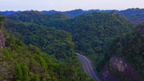 Ascending-drone-shot-of-car-driving-between-vegetated-mountains-of-Las-Terrenas,Dominican-Republic