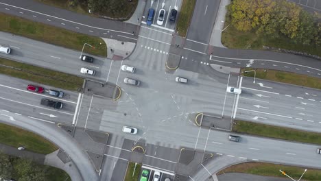 Calm-suburban-road-intersection-with-cars-driving-straight-forward-in-both-directions,-top-down