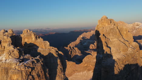 Revealing-cinematic-drone-of-the-Tre-Cime-di-Lavaredo-in-Italy,-with-wilderness-mountain-ranges-in-the-distance