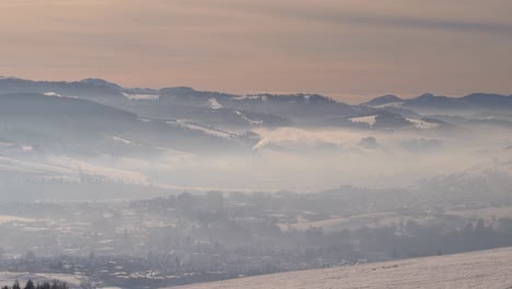 Look-out-towards-fog-and-haze-covered-village-in-valley-with-industry-in-winter