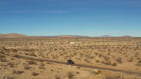 An-off-highway-vehicle-driving-along-dirt-trails-in-the-Mojave-Desert-landscape---aerial-view