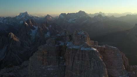 Revealing-drone-shot-of-Tre-Cime-di-Lavaredo-a-mountain-range-in-Italy,-with-the-sun-setting