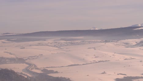 Totale-Eines-Kleinen-Dorfes,-Umgeben-Von-Schnee-Im-Winter-Mit-Bergen-Im-Hintergrund