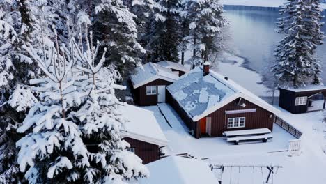 Winter-Scenery-With-Snow-And-Cabins-In-Norway---aerial-pullback