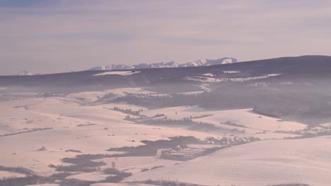 Static-view-of-wide-open-winter-landscape-with-tall-mountains-in-background
