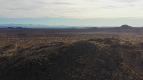 Rugged-mountain-ridgeline-overlooking-the-Mojave-Desert-basin---sliding-aerial-view