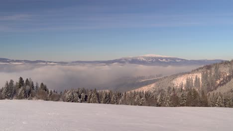 Beautiful-view-over-winter-landscape-with-trees,-cloud-inversion-in-distance-and-mountain