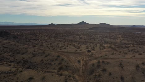 Fahren-Eines-Off-Highway-Fahrzeugs-Eine-Steile-Steigung-Hinauf,-Um-Das-Zerklüftete-Gelände-Der-Mojave-Wüste-Zu-Enthüllen---Luftbild