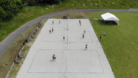 Aerial:-drone-shot-of-beach-volley-among-lush-landscape-with-green-trees-while-people-are-playing-beach-volley-in-the-sand