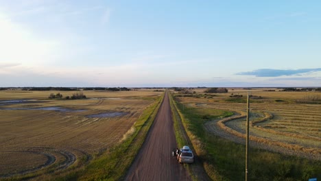 Rückwärts-Fliegende-Drohne,-Die-Einen-Silbernen-Minivan-Enthüllt,-Der-Entlang-Einer-Langen-Und-Endlosen-Unbefestigten-Straße-In-Flagstaff-County,-Alberta,-Geparkt-Ist