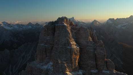 Rotating-cinematic-drone-shot-of-Tre-Cime-di-Lavaredo-in-Italy,-centering-on-a-rocky-peak-with-mountain-wilderness-all-around