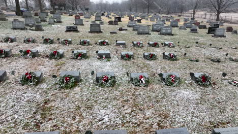 Funeral-graveyard-cemetery-headstone-markers-decorated-with-Christmas-wreaths-during-snow-storm