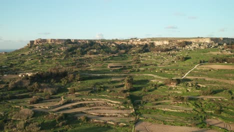 AERIAL:-Green-Hill-Patterned-with-Farm-Lands-on-a-Rocky-Mountain-Slope-in-Malta