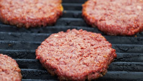 Barbecuing-plant-based-Impossible-Burger-patties-on-electric-grill-semi-close-up-shot-panning-up-and-around-to-reveal-numerous-patties-browning-as-they-cook---in-Cinema-4k-