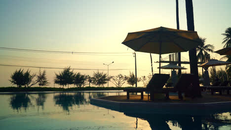 umbrella-with-bed-pool-around-swimming-pool-with-ocean-sea-background-at-sunset-or-sunrise-time---holiday-and-vacation-concept