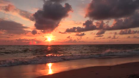 Dramatischer-Sonnenaufgang-Am-Strand,-Der-Den-Himmel-Verbrennt,-Sonne-Scheint-In-Roter-Farbe-Während-Des-Idyllischen-Meereshintergrundes