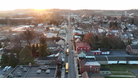 Aerial-tracking-of-two-yellow-school-bus-through-town-in-USA-at-dramatic-sunrise