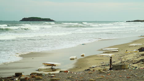 Styrofoam-trash-pollution-on-beach-as-ocean-waves-roll-into-shore-on-gloomy-day