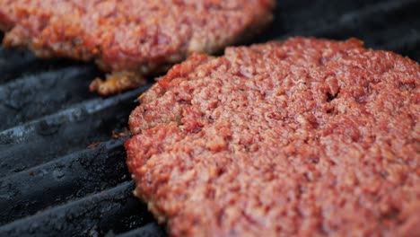 Barbecuing-plant-based-Impossible-Burger-patties-on-electric-grill-close-up-shot-panning-down-and-over-to-reveal-another-patty-turning-brown-as-they-cook---in-Cinema-4k-