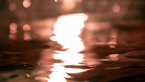 Slow-motion-water-waves-background-reflecting-light-during-sunset-or-sunrise,-ripple-h2o-background