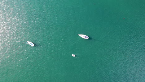 Slow-moving-aerial-shot-looking-down-over-beautiful-Pacific-Ocean-with-rowing-and-sailing-boats-and-the-sun-beating-down-on-the-water