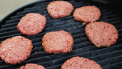 Barbecuing-plant-based-Impossible-Burger-patties-on-electric-grill-wide-shot-panning-up-showing-8-seasoned-burgers-freshly-placed-on-the-grill---in-Cinema-4k-