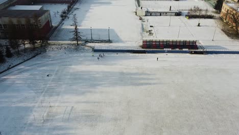 Gruppe-Von-Läufern,-Die-Sich-Auf-Einem-Schneebedeckten-Sportplatz-Aufwärmen,-Winteraufwärmdrohnenaufnahme