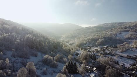 Atemberaubender-Frostiger-Wald,-Weiße-Bäume,-Kleines-Dorf-Und-Atemberaubende-Luftaufnahme-Der-Morgensonne