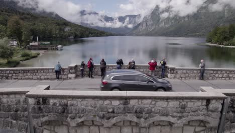 Video-with-drone-of-plane-discovery-of-crane-ascending-in-Lake-Bohinj-with-the-bridge-in-the-foreground-with-people-passing-by-and-vehicles