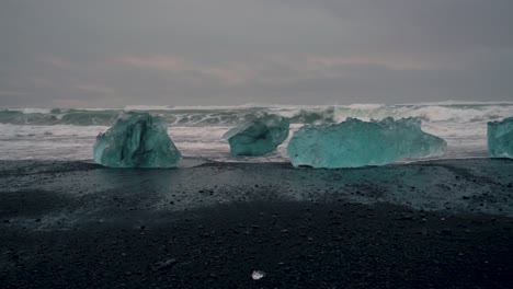 Toma-Panorámica-Que-Muestra-Vastos-Icebergs-Extremos-En-La-Costa-Del-Océano-Con-Playa-De-Arena-Negra-En-Islandia