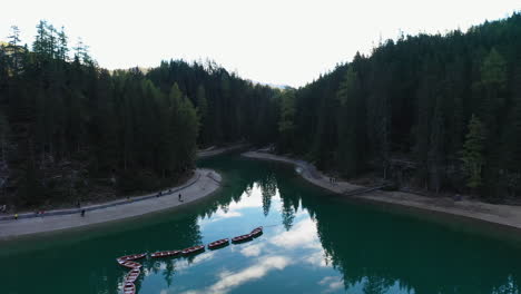 Drone-shot-of-wooden-boats-tied-up-at-the-beautiful-Lago-Di-Braies,-Italian-Dolomites,-in-South-Tyrol-Italy