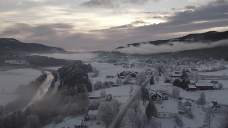 Frozen-winter-village-with-low-clouds-and-a-river