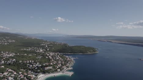 Video-with-Front-Plane-Drone-advancing-over-the-coast-of-Jadranovo-in-Croatia,-clear-sky-with-some-clouds,-you-can-see-a-pier-with-boats-on-the-shore