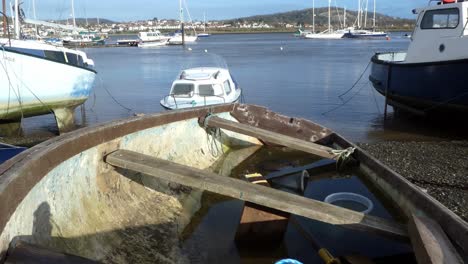Small-weathered-fishing-boat-in-harbour-town-filled-with-water-disused-and-flooded-seafront