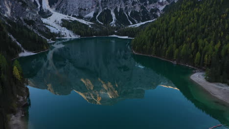 Cinematic-tilting-upward-drone-shot-of-the-beautiful-Lago-Di-Braies,-Italian-Dolomites,-in-South-Tyrol-Italy