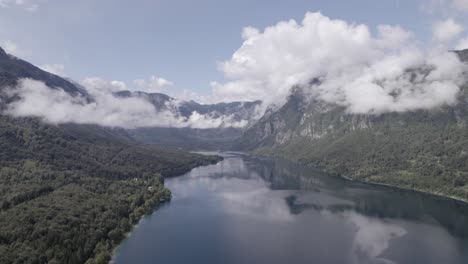 Frontal-drone-video-over-Lake-Bohinj-advancing-towards-its-interior-between-the-mountains,-the-sky-is-clear-with-some-clouds