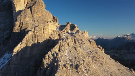 Revealing-drone-shot-of-Tre-Cime-di-Lavaredo-a-mountain-range-in-Italy,-starting-close-on-a-rocky-side-of-the-mountain