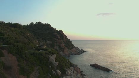 Drone-footage-of-east-Sardinia-coastline-during-colourful-sunset,-Red-Rocks-in-the-Ogliastra-region-tourist-attraction-of-the-Golfo-di-Orosei