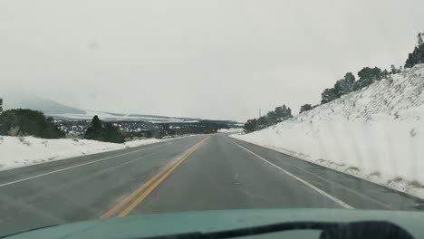 Interior-view-of-a-car-driving-through-a-highway-in-a-cold-and-snowy-landscape