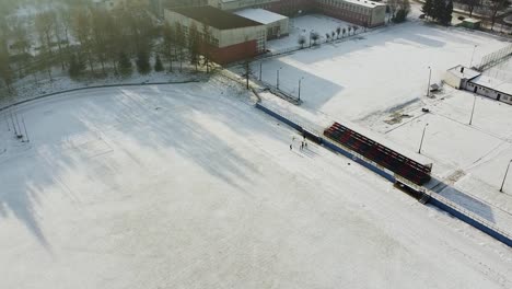 group-of-runners-exercising-on-snowy-running-track,-winter-exercising-drone-shot