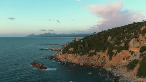 Aerial-view-of-East-wild-Sardinia-coastline-cliff-rock-bound-formation-during-colorful-sunset