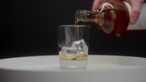 Scotch-being-poured-over-ice-cubes-in-a-scotch-glass