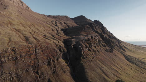 Amplio-Paralaje-Aéreo-Alrededor-De-Una-Cascada-Distante-En-La-Hendidura-De-Los-Acantilados-Rocosos-De-Islandia
