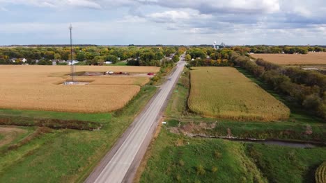 aerial-view-of-a-highway-surrounded-by-cornfields-and-a-cellphone-tower-in-the-midwest-during-the-autumn-season