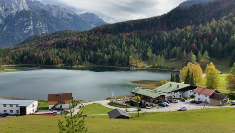 Toma-Panorámica-Del-Lago-Lauter-Con-Posadas-Y-Picos-De-Las-Montañas-Karwendel-En-El-Fondo,-Muy-Cerca-De-La-Ciudad-Bávara-De-Mittenwald-En-Alemania