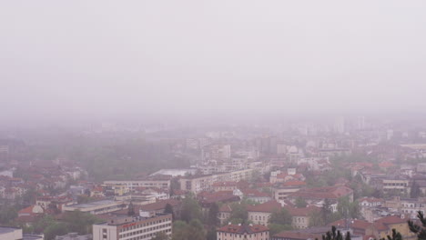 4K-footage-of-the-town-of-Vratsa,-Bulgaria,-and-the-surrounding-mountain-Stara-Planina-,-while-a-deep-fog-covers-the-town