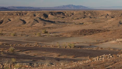 A-male-hiker-treks-through-the-Arizona-desert,-seen-in-a-wide-shot-from-afar