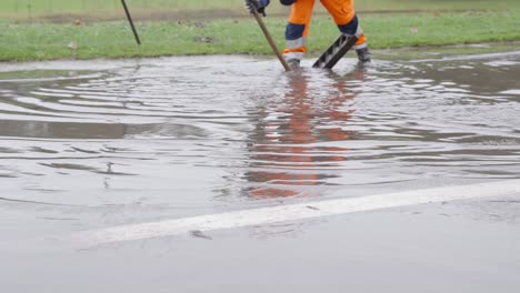 City-Street-Workers-Declogging-Manhole-Drainage-To-Drain-Floodwater